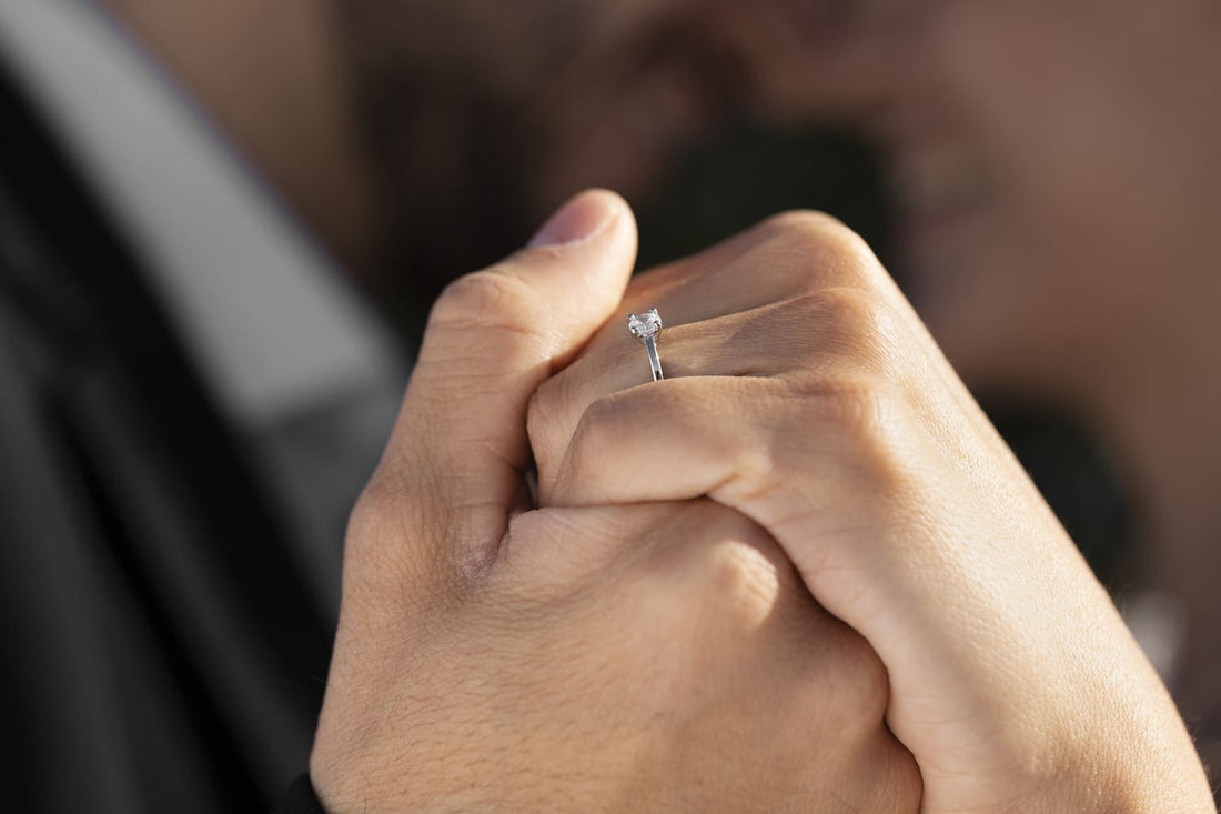 Close-up of a couple holding hands, showcasing a beautiful moissanite ring on the woman’s ring finger, highlighting the elegance of classic engagement rings.